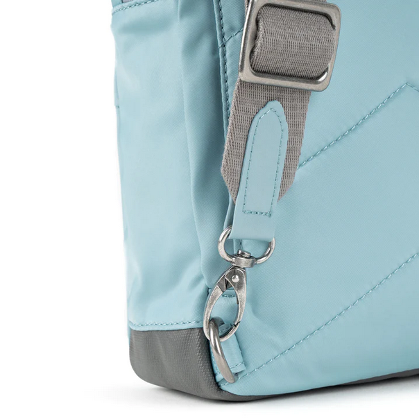 Light blue sling bag close-up of strap hardware, carabiner, and zip pull