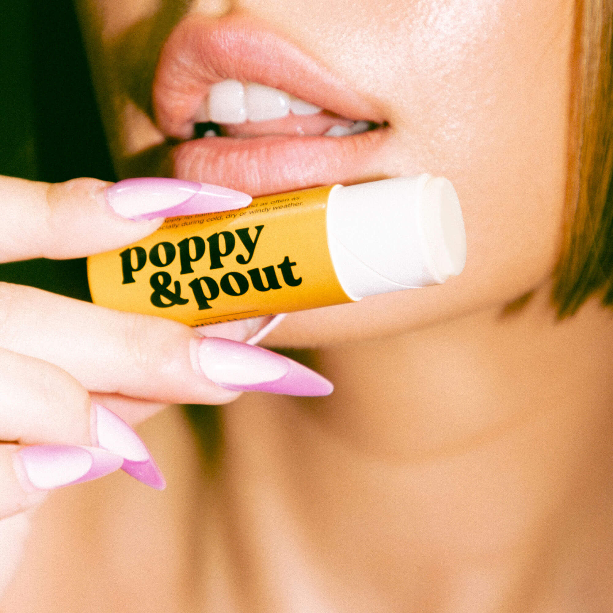 Lip balm being applied from a yellow tube; white balm on lips