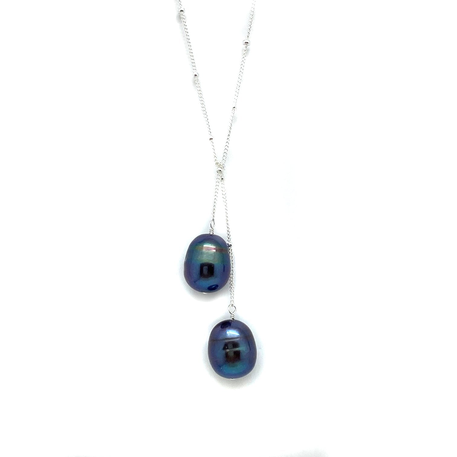 Silver lariat necklace with two dark iridescent blue pearls, dangling drop