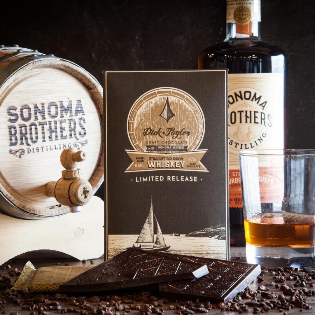Dick Taylor dark chocolate gift box with bourbon whiskey theme, plus scattered chocolate pieces