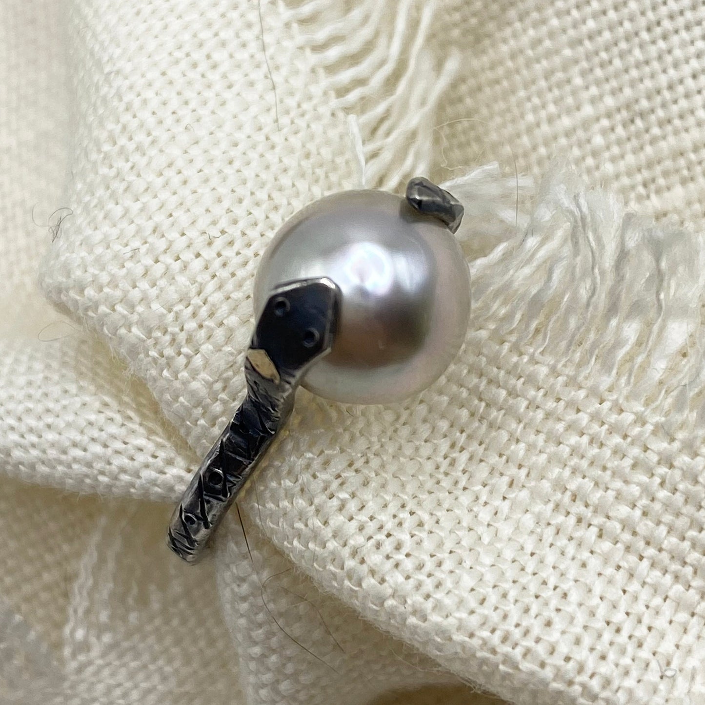 Sterling silver snake ring with Tahitian pearl and dark scale-textured band, side view
