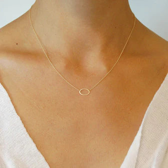 Gold oval pendant necklace on neckline, delicate chain with small mini oval charm