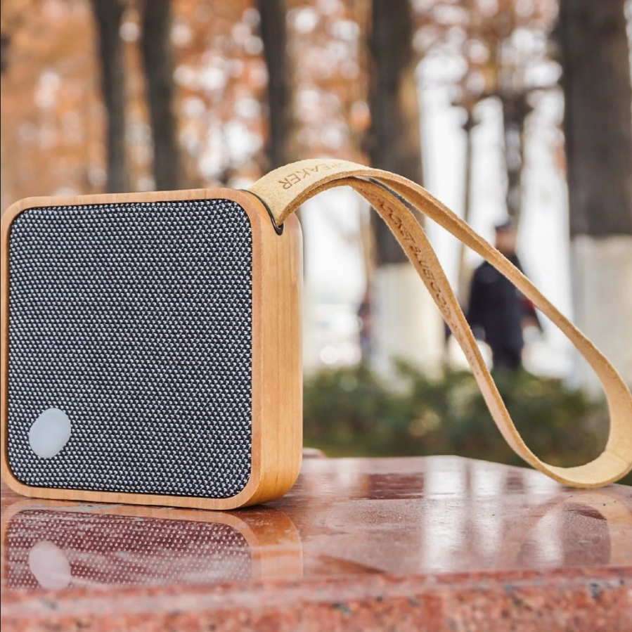 Square bamboo Bluetooth speaker with dark fabric grille and wrist strap