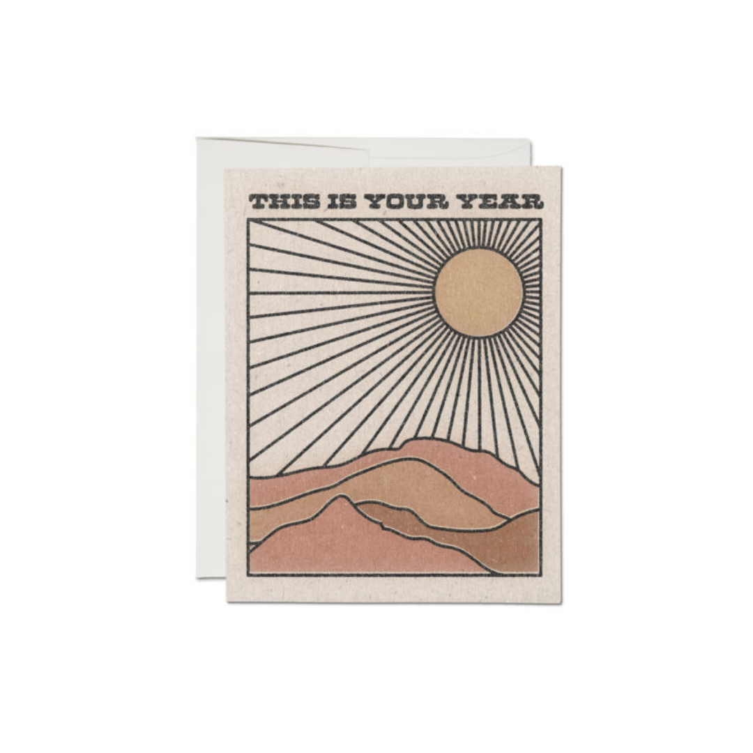 Greeting card front with 'This Is Your Year' text, sun and mountain design