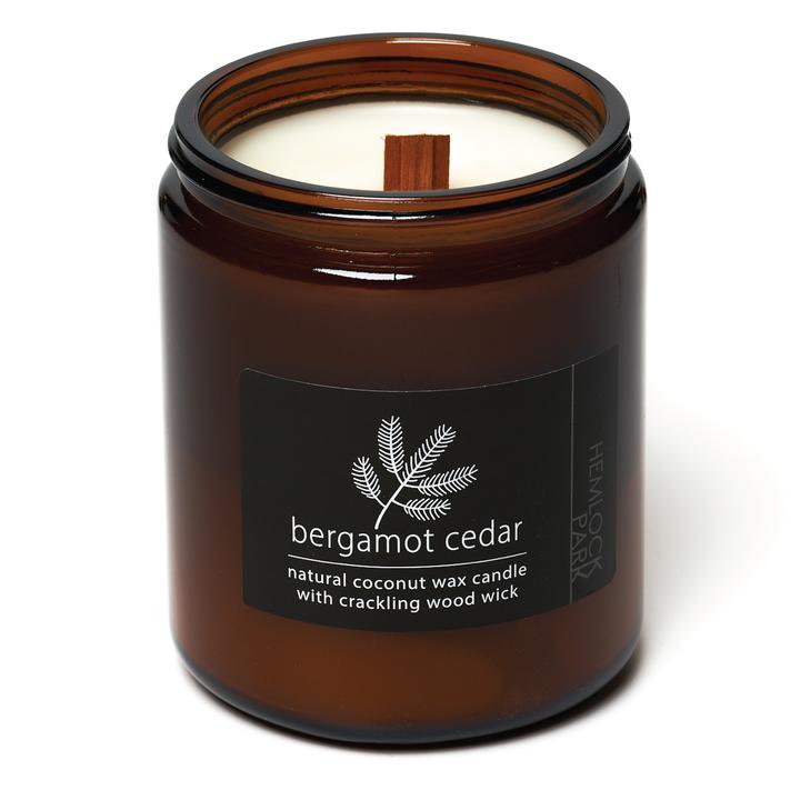 Coconut wax candle in amber jar with wood wick, bergamot cedar scent label