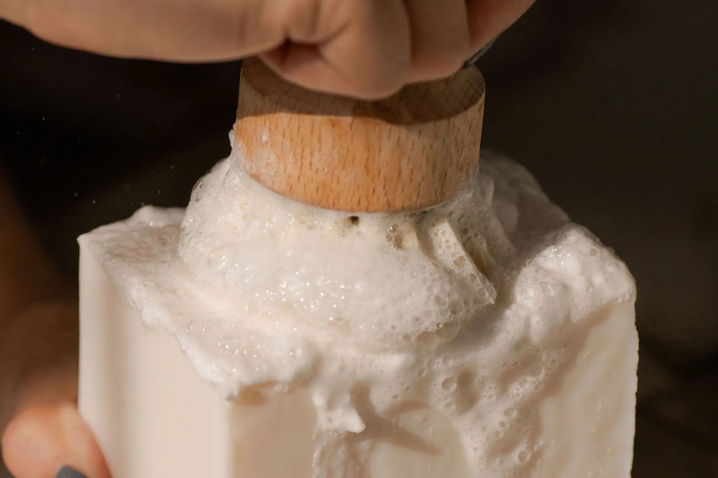 Large dish washing block with wooden brush head and white foam close-up