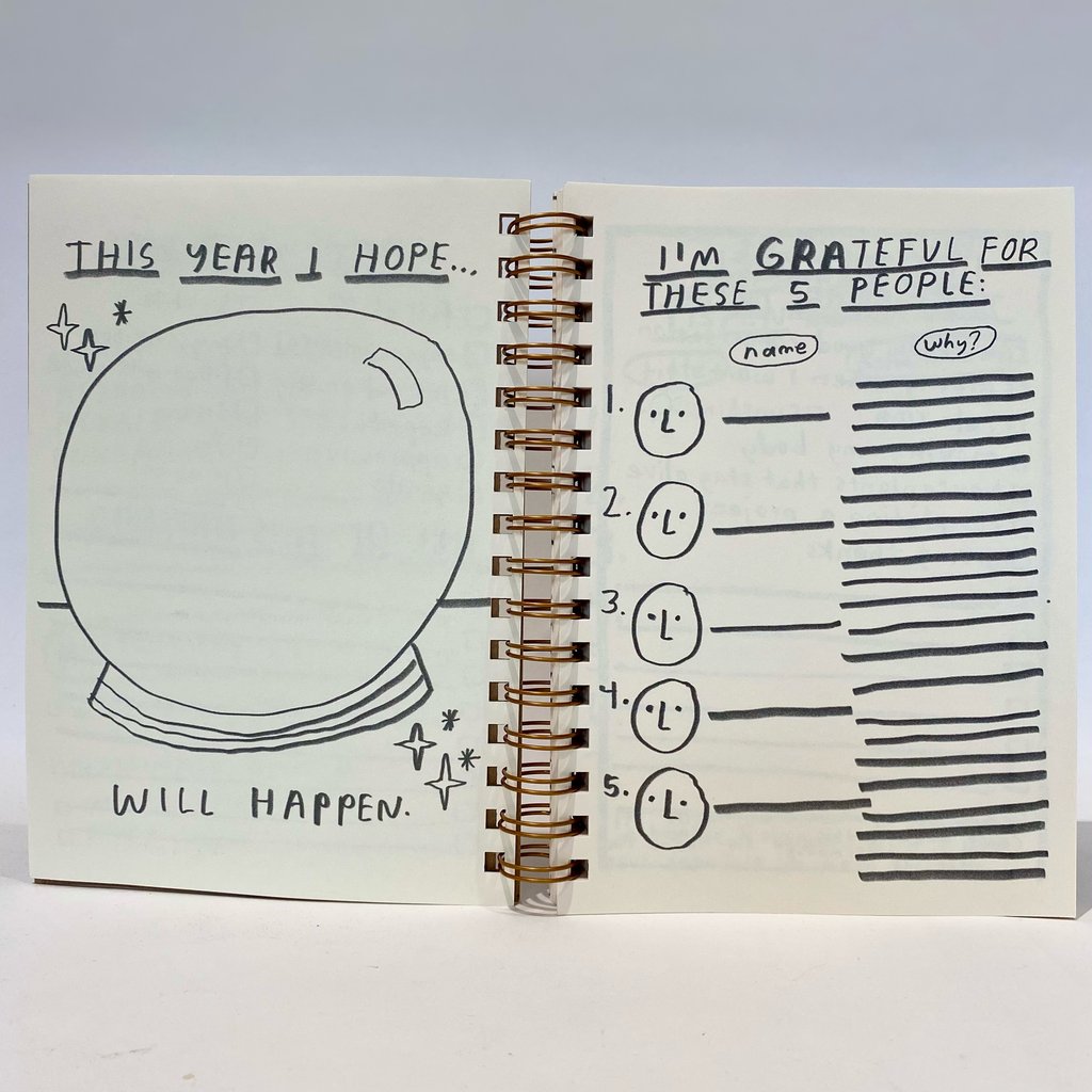 Open 12 month planner pages with hand-drawn text and icons; spiral binding visible