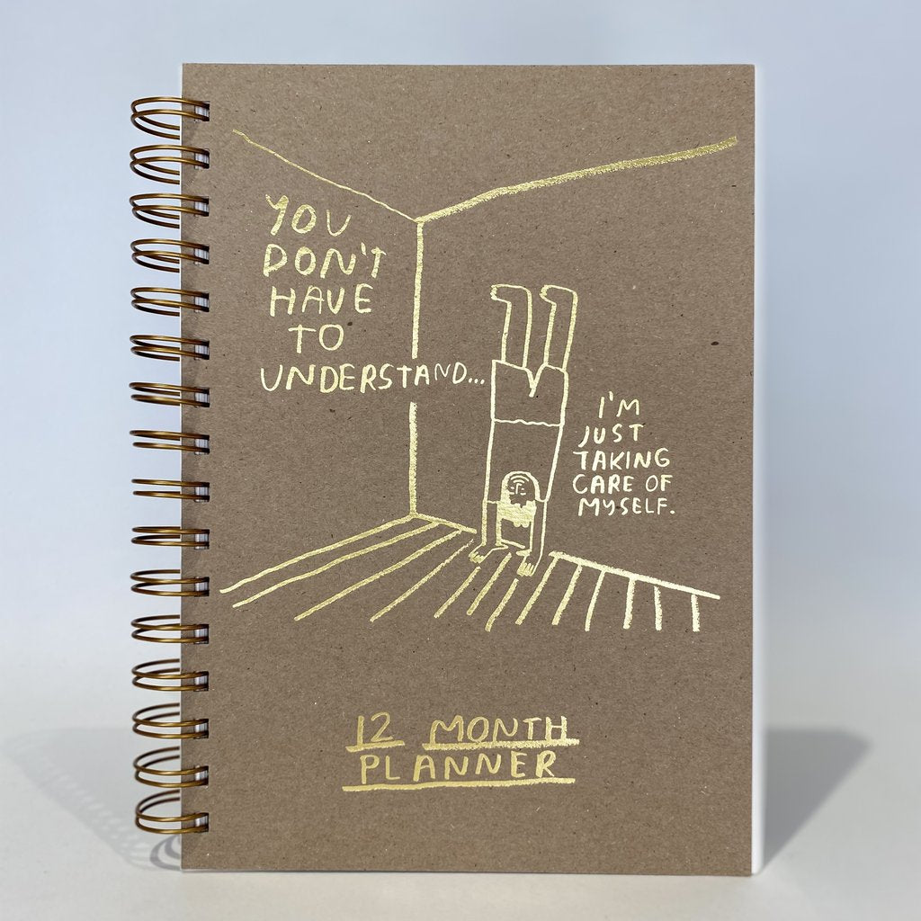 12 month planner notebook with spiral binding and brown cover, motivational line-art text in yellow