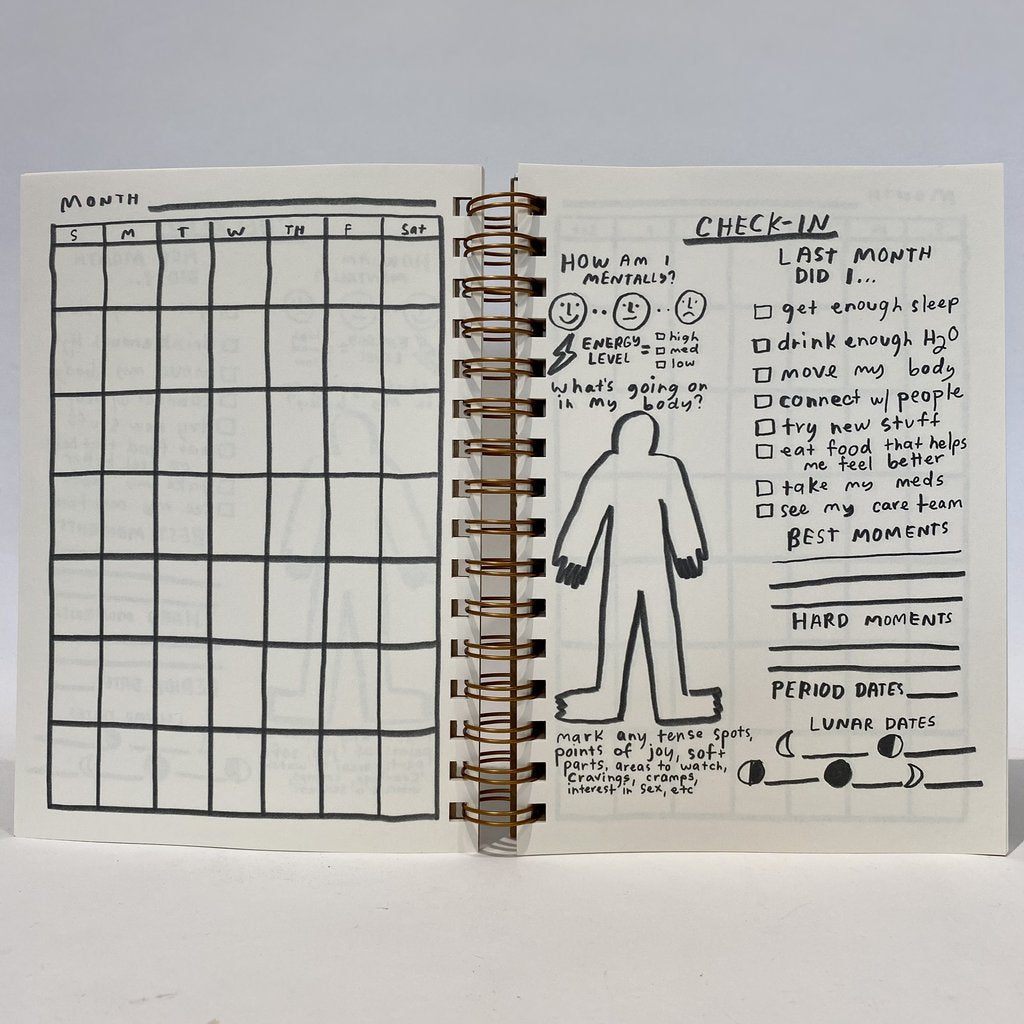 Open 12 month planner pages with monthly grid and check-in checklist; spiral binding visible