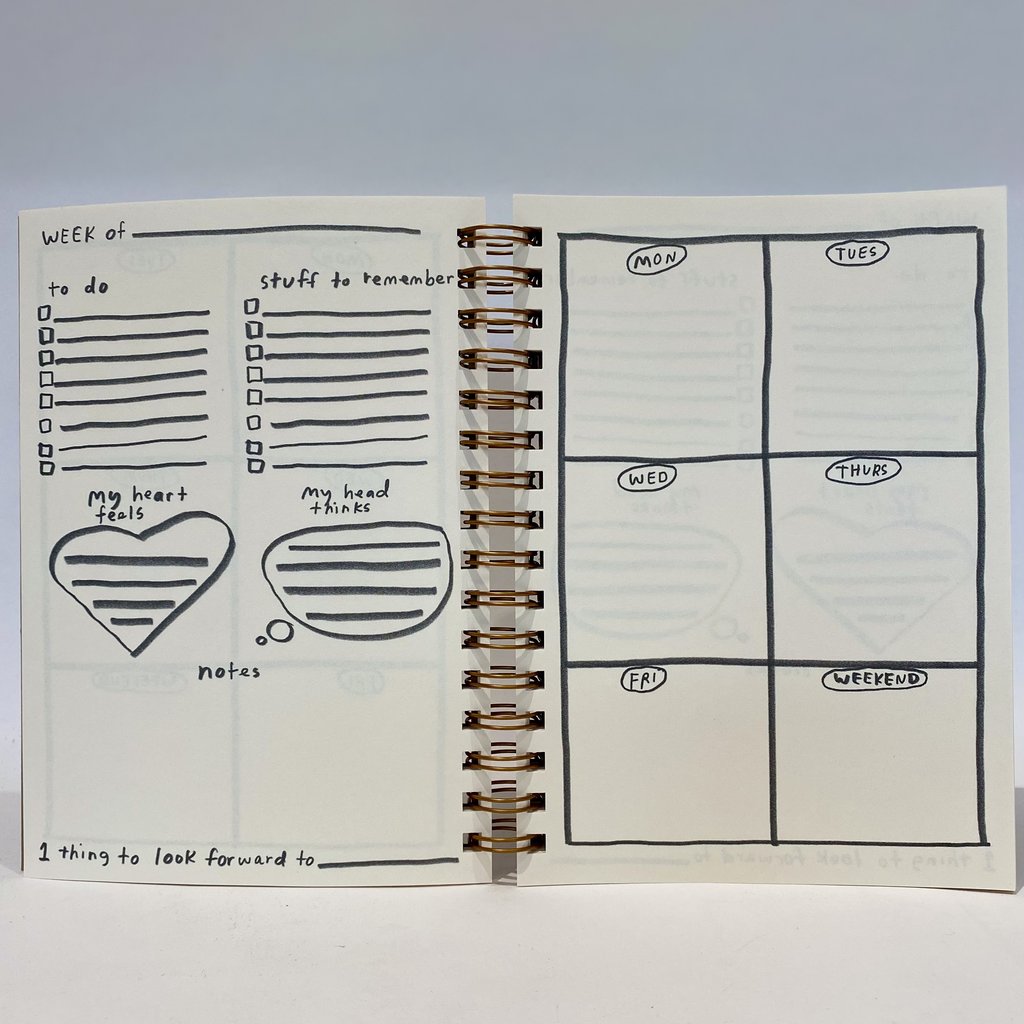 Open 12 month planner weekly layout page with to-do lines and heart notes; spiral binding visible
