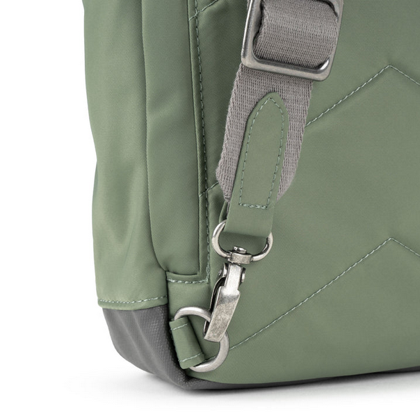 Sage green sling bag close-up of adjustable strap, metal clips, and stitched seam