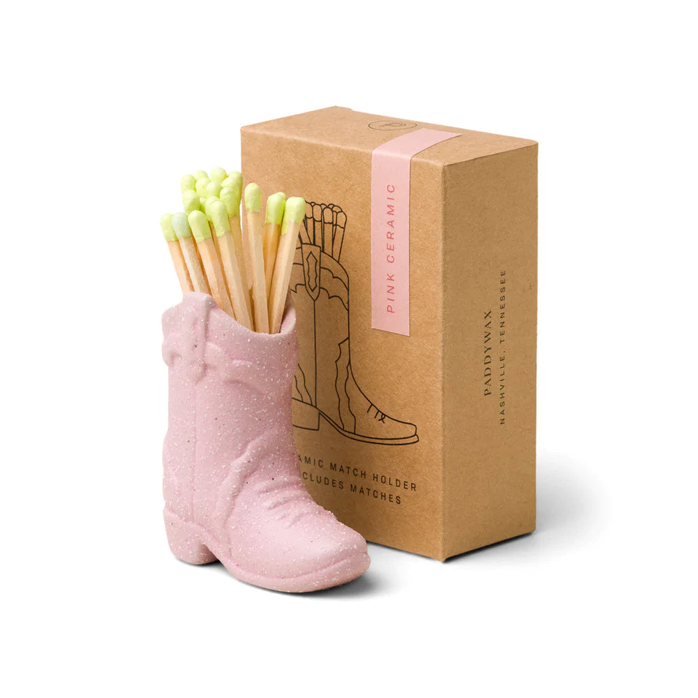 Ceramic cowboy boot match holder in pink, holding green-tipped wooden matches