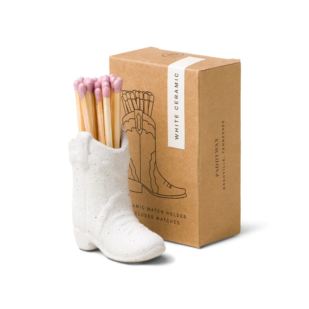 Ceramic cowboy boot match holder in white, holding purple-tipped wooden matches