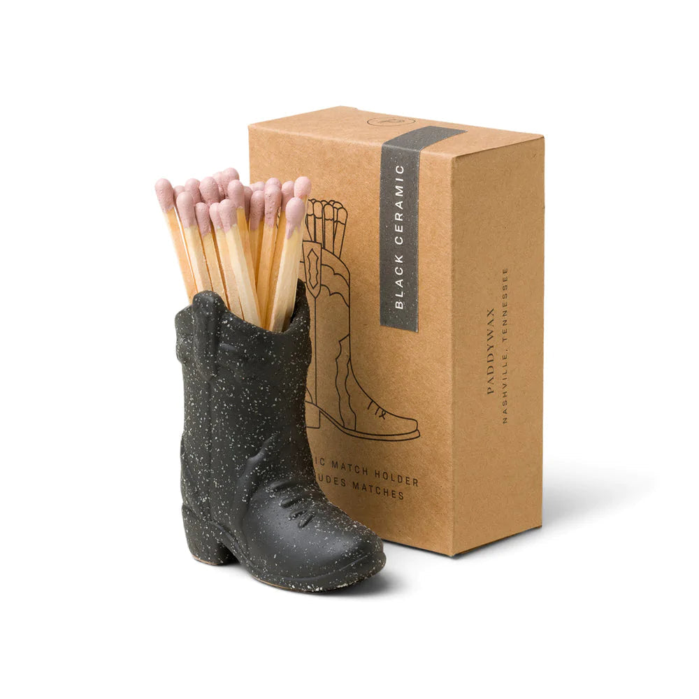 Ceramic cowboy boot match holder in dark gray-black, holding pink-tipped wooden matches