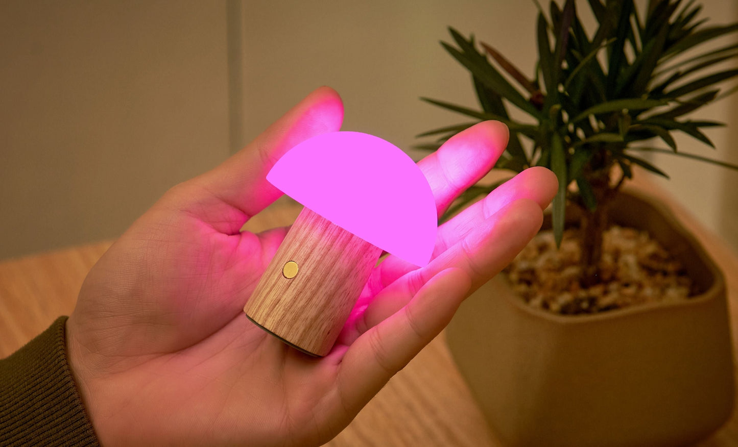 Ash wood mushroom LED lamp with pink glowing cap, shown in hand