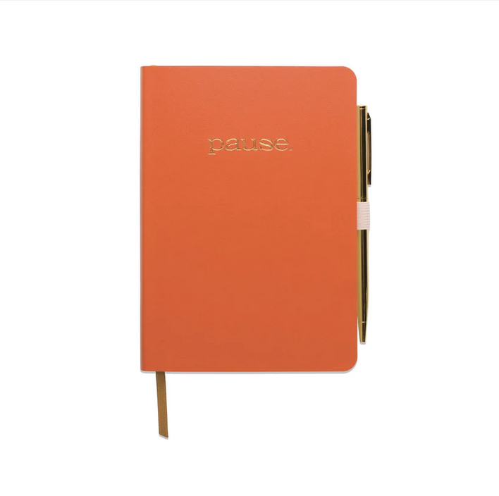 Orange gratitude journal with 'pause.' cover and attached gold pen