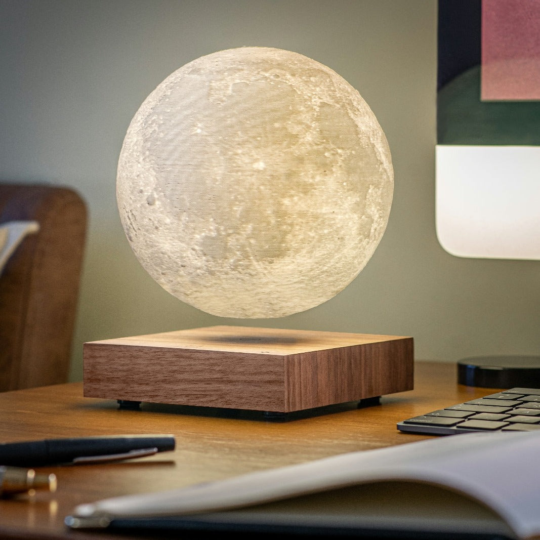 Moon-shaped lamp with glowing white sphere and walnut wood base