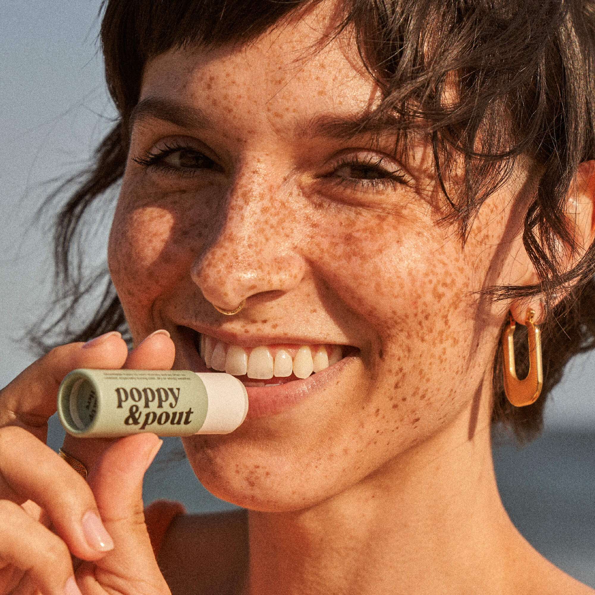 Mint lip balm tube held near lips, ready to apply