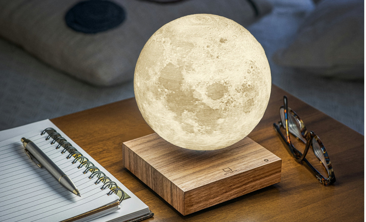 Moon-shaped lamp with glowing white sphere on walnut wood base