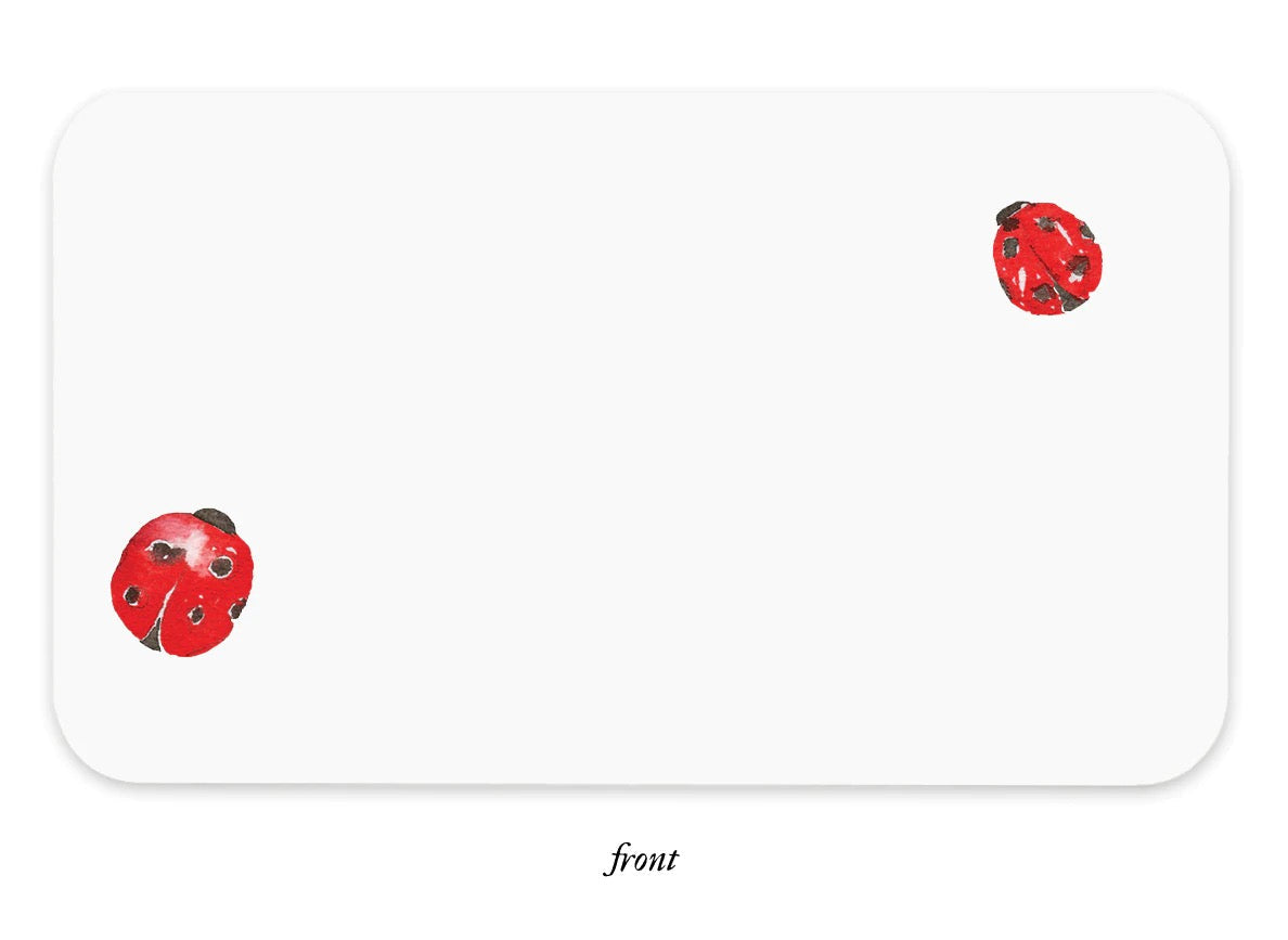 White notebox front with scattered ladybug stickers in red and black, rounded corners