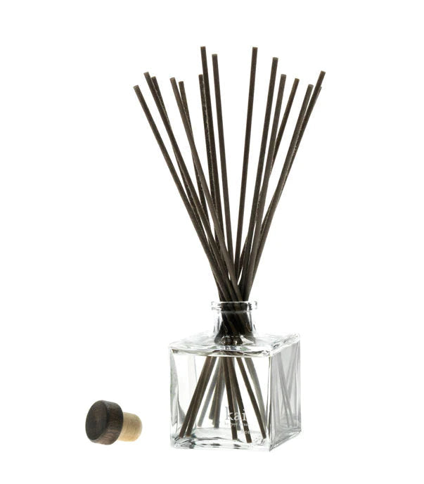 Clear glass home diffuser with dark reed sticks and metal cap