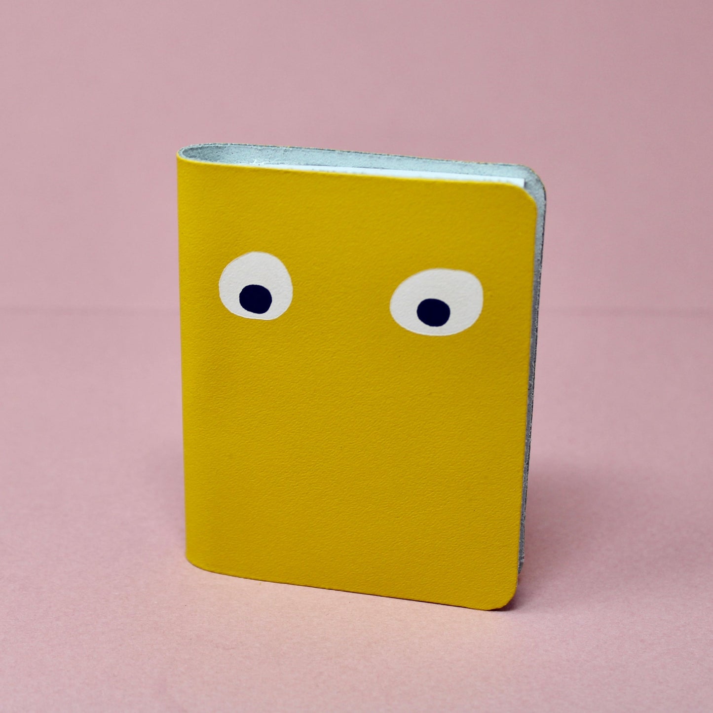 Yellow mini leather notebook with two white googly eyes on the cover