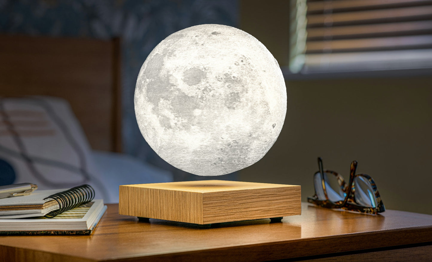 Moon-shaped lamp with glowing white sphere on warm wood base