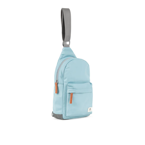 Light blue sling bag with adjustable strap, front pocket, and stitched panel details