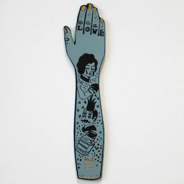 Tattooed arm bookmark in heritage blue with illustrated dark-ink character art